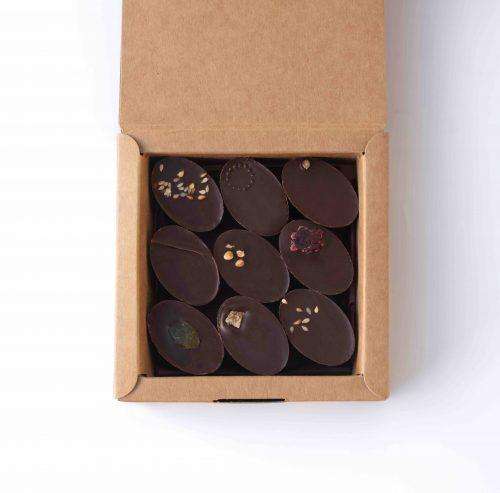 Boîte ouverte de 9 chocolats individuels, fourrés avec des ganaches et pralinées