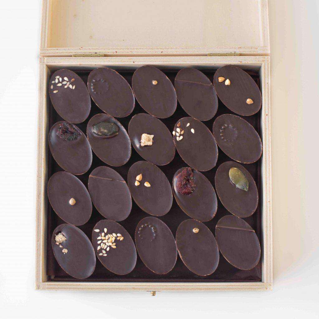 boîte en bois ouverte de 20 chocolats individuels, fourrés avec des ganaches et des pralinés