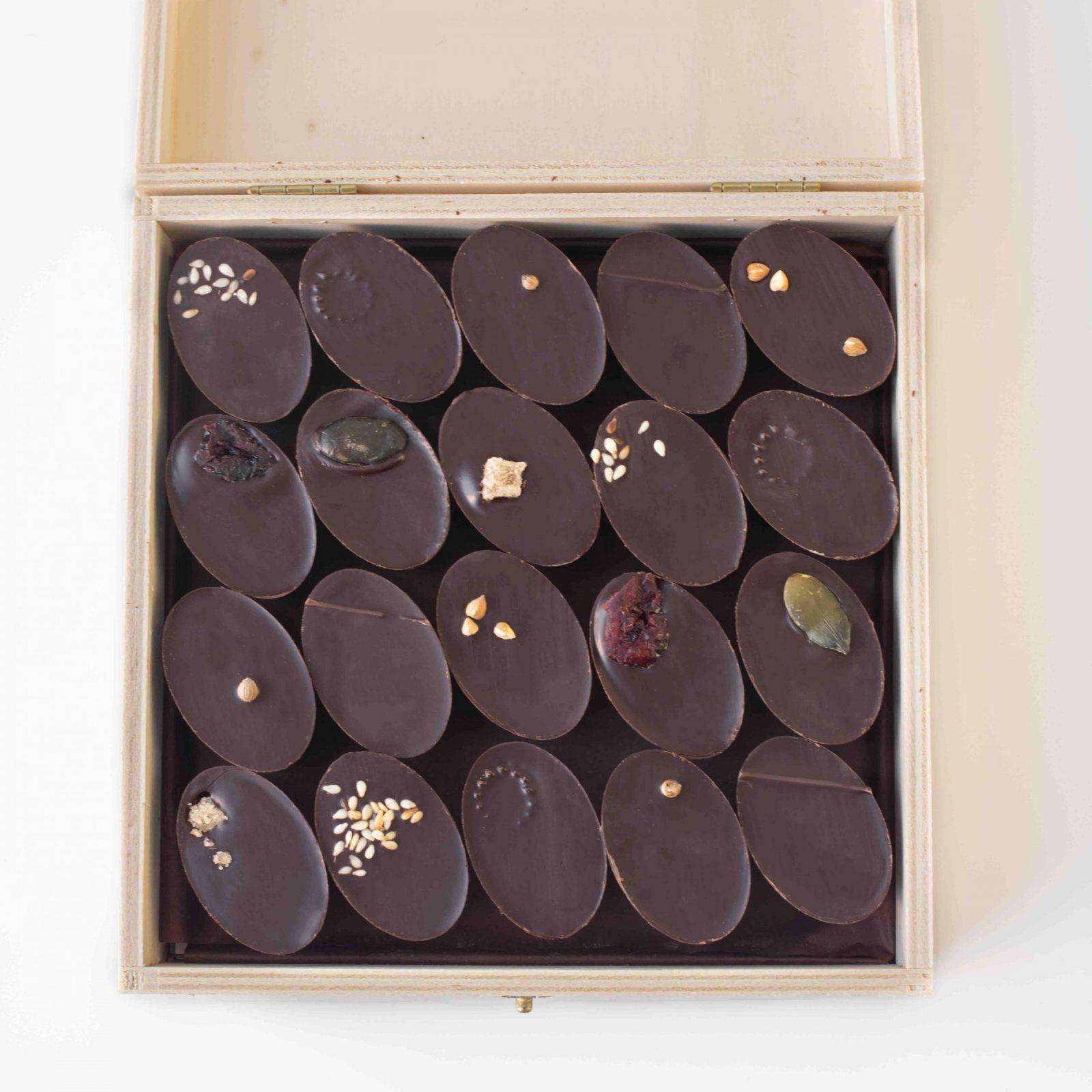 boîte en bois ouverte de 20 chocolats individuels, fourrés avec des ganaches et des pralinés