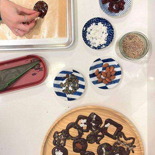 assiettes avec des toppings en haut et poche à douille rempli de chocolat à gauche et mendiants de chocolat décorés en bas