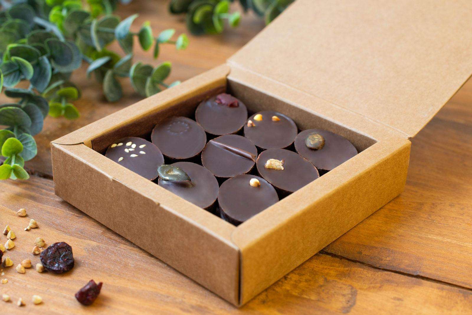 Boîte de 9 chocolats individuels dans une boîte ouverte en kraft sur une table en bois